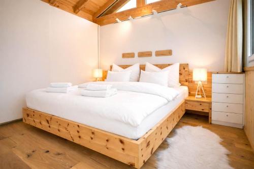 a bedroom with a large bed with white sheets at Tyrolschalet LITTLE LUCK - Private Pool & Mountain View in Rofansiedlung