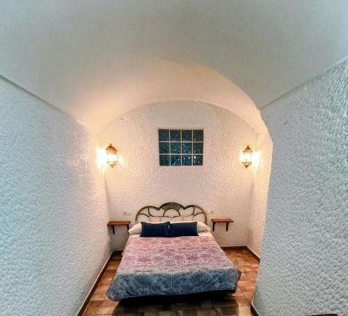a bedroom with a bed in a room with a window at Cuevas Uropia in Graena