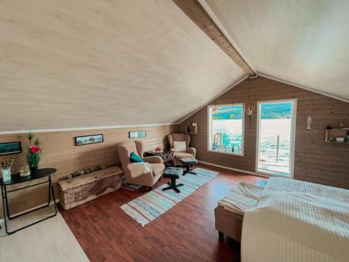 a large room with a bed and chairs and windows at Unique boathouse with a spectacular view in Oldra
