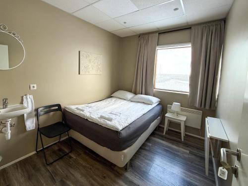 a small bedroom with a bed and a window at Við Hafið Oceanfront Guesthouse in Ólafsvík