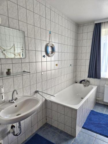 a white bathroom with a tub and a sink at Ostsee Pension Pohnsdorfer Mühle in Sierksdorf