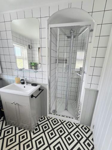 a white bathroom with a shower and a sink at 12 Ivy Cottage in St Ives