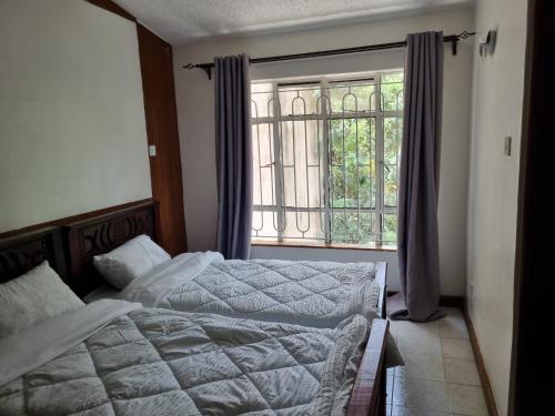 a bedroom with two beds in front of a window at WeniZani Backpackers Hostel Nairobi in Nairobi