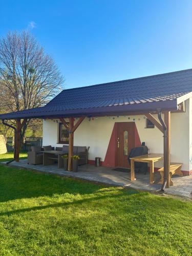 a pavilion with a picnic table and a house at Urocze Roztocze Jacnia - domek 1 in Jacnia