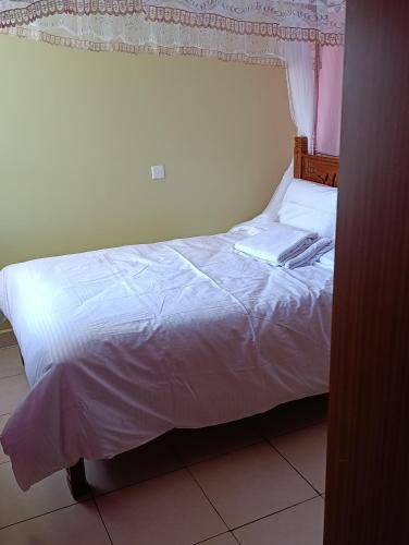 a bedroom with a bed with white sheets at Greatwall golden stay in Machakos