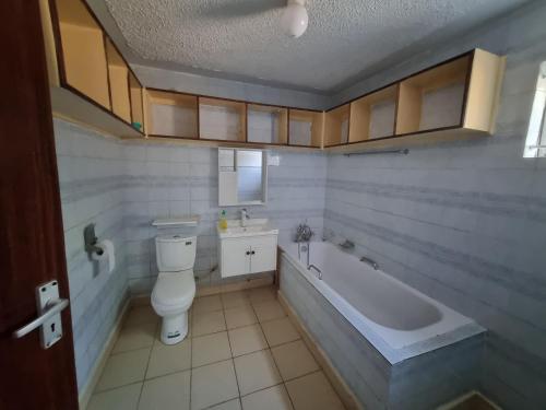 a bathroom with a tub and a toilet and a sink at WeniZani Backpackers Hostel Nairobi in Nairobi