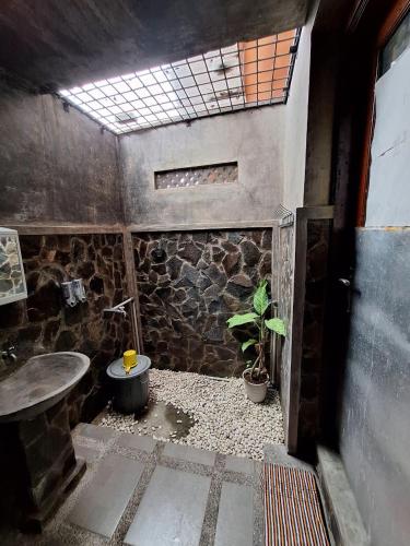 a stone bathroom with a sink and a plant at Palanta Roemah Kajoe Syariah Villa in Kampungdurian