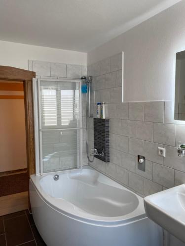 a white bath tub in a bathroom with a sink at Hellwig Ferienwohnung 1 in Bernburg