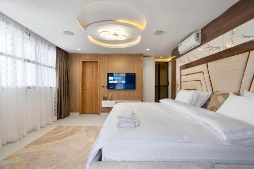 a bedroom with a large white bed and a television at Saka in Lekki