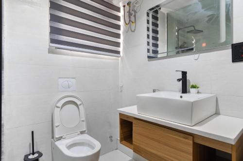 a white bathroom with a sink and a toilet at Saka in Lekki