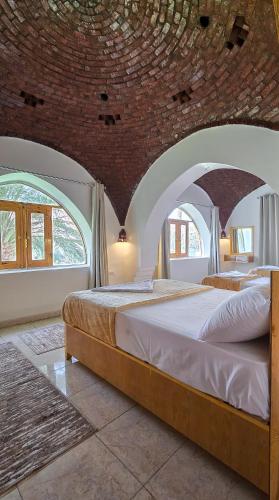two beds in a room with a brick wall at Luxor Family Home in Naj‘ ar Rizqah