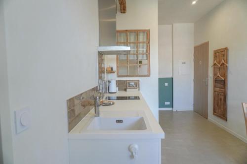 a white kitchen with a sink and a hallway at Bed & Breakfast Perbos 1556 in Labastide-Clairence