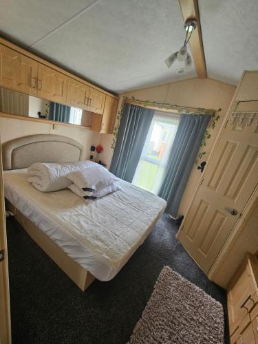 a small bedroom with a bed and a window at V10 static caravan in Ingoldmells