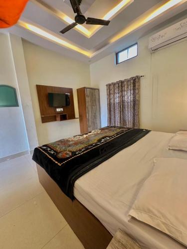 a bedroom with a large bed with a ceiling fan at Riskla hotel Near-Ram Mandir 700M in Ayodhya