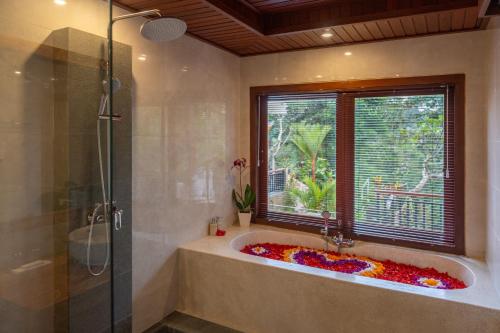 a bathroom with a bath tub with a window at Tirtha Dawa Villa in Tegalalang