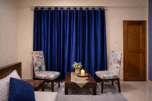 a living room with blue curtains and a table and chairs at Himnest in Kalpa