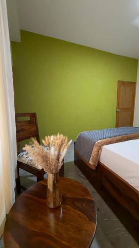 a room with a table with a bed and a vase with flowers at Himnest in Kalpa