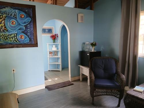 a living room with a chair and a painting on the wall at CROOКED TREE LODGE Belize in Crooked Tree