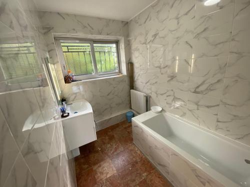 a white bathroom with a tub and a sink at La Maison Bloom in Houilles