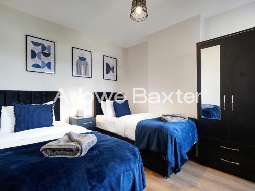 two beds in a bedroom with blue sheets at Watford Large 5BR Home - Contractors & Families in Watford