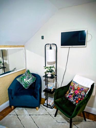 a living room with two chairs and a tv on the wall at Comfy Bedroom and Private Bathroom on the Top Floor of a Home Stay -10 mins walk to the center - Off street parking in Cork
