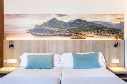 a bedroom with two beds with a painting on the wall at Hostal Nadal in Sóller