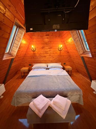 a large bed in a wooden room with two towels at Twin Cabins Azuga in Azuga