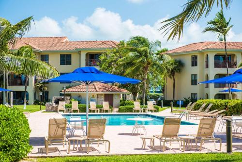 a resort with a pool with chairs and umbrellas at Georgetown Villas 201 - 2BR Oceanfront - Reef Snorkel & Walk to Restaurants in George Town