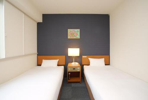 a room with two beds and a table with a lamp at Smile Hotel Towada in Towada