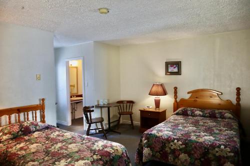 a hotel room with two beds and a table and a desk at Bennett Lodge in Daniels Harbour