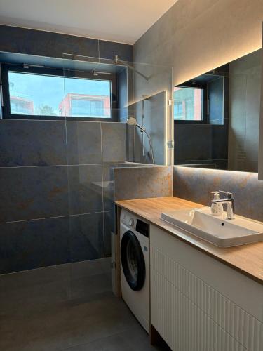a bathroom with a sink and a washing machine at BL Residence Balatonlelle in Balatonlelle