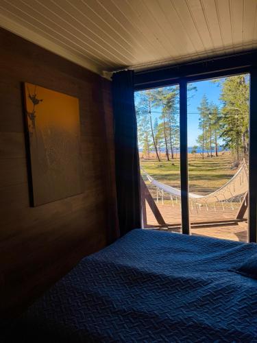 a bedroom with a bed and a large window at Hidden Hiiumaa Seaside Cottage in Kõrgessaare