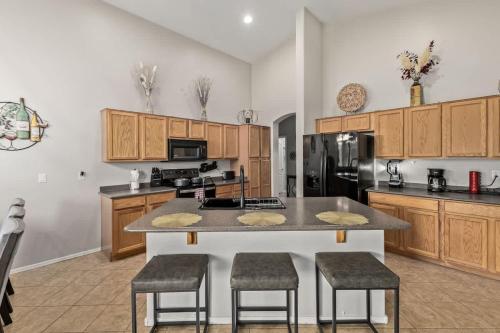 a kitchen with wooden cabinets and a large island with bar stools at Pet-Friendly 4BR Oasis - Heated Pool Firepit & BBQ in Chandler