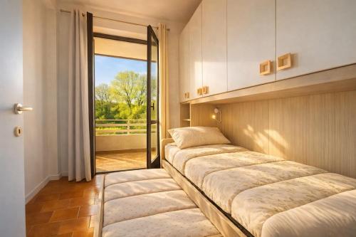 a row of beds in a room with a window at LaBohème Lake Maggiore Retreat with Private Beach in Dormelletto