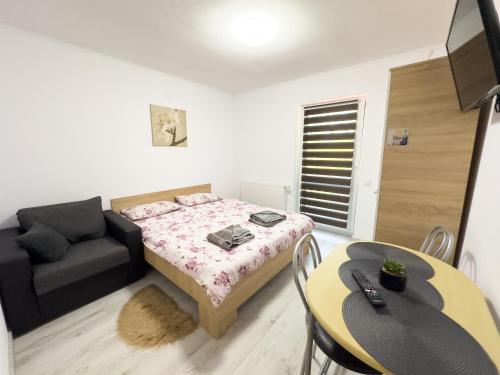 a bedroom with a bed and a couch and a table at Pensiunea NikoBella Panzió in Sovata