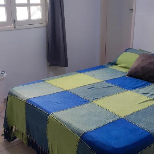 a bed with a blue yellow and green quilt on it at Casa Bela in Itamaracá