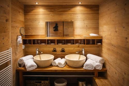 a bathroom with two sinks and towels on a wooden wall at Hôtel Chalet Alpage in La Clusaz