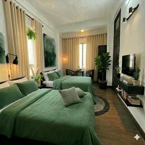 a bedroom with two green beds and a living room at Muse Riverside in Ninh Binh