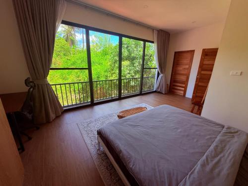 a bedroom with a bed and a large window at Sharing Pool Villa Sritanu in Ko Phangan