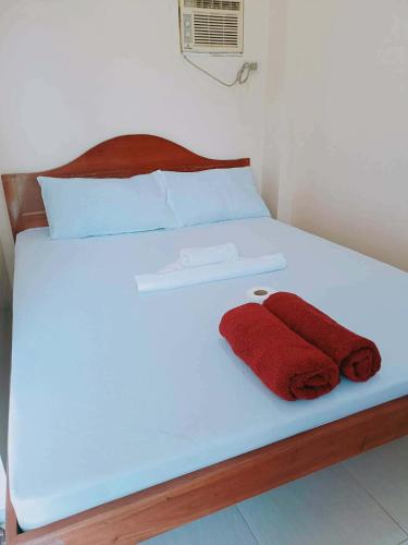 a white bed with two red towels on it at Lake Lovers Stay Hostel in Badian
