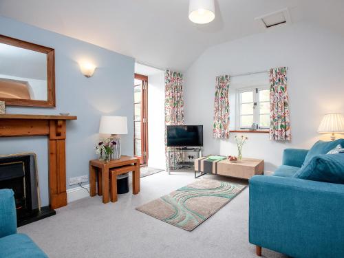 a living room with a blue couch and a fireplace at Tuckenhay, 4 Castle Cottage- Fcn in Ashsprington