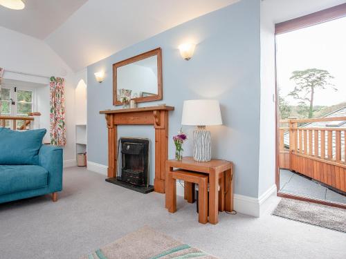 a living room with a fireplace and a blue couch at Tuckenhay, 4 Castle Cottage- Fcn in Ashsprington
