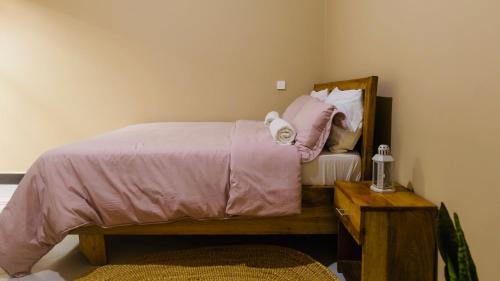 a bedroom with a bed with pink sheets and a mirror at Sakina Nook in Arusha