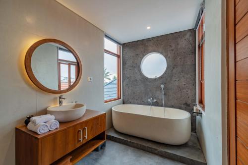 a bathroom with a tub and a sink and a mirror at Cahya Restu Ubud Villa in Ubud