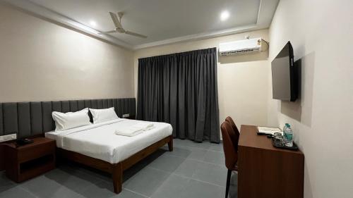 a bedroom with a bed and a desk and a television at Rangoli Suites & Restrobar in Bantvāl