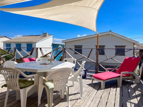 a table and chairs on a deck with an umbrella at L'authentique chalet en bois sur pilotis in Gruissan