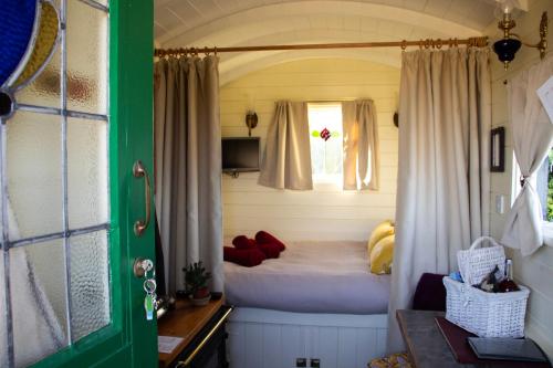 a small bedroom with a bed and a window at Halcyon - Shepherd's Hut in Northrepps