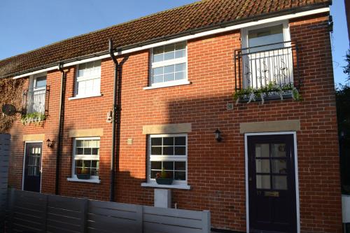 a red brick house with white windows and a door at Frinton Escapes - The Cottage in Frinton-on-Sea