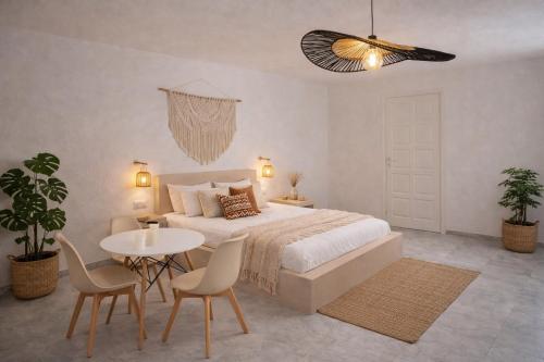 a bedroom with a bed and a table and chairs at Noème Santorini in Perissa