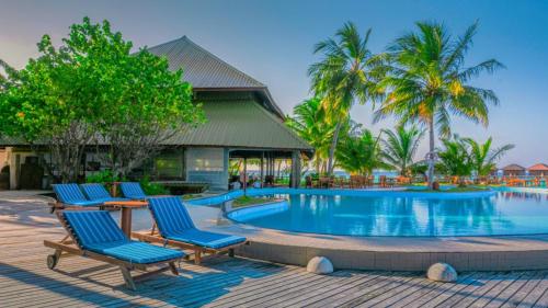 a swimming pool with blue chairs and palm trees at Filitheyo Island Resort in Filitheyo